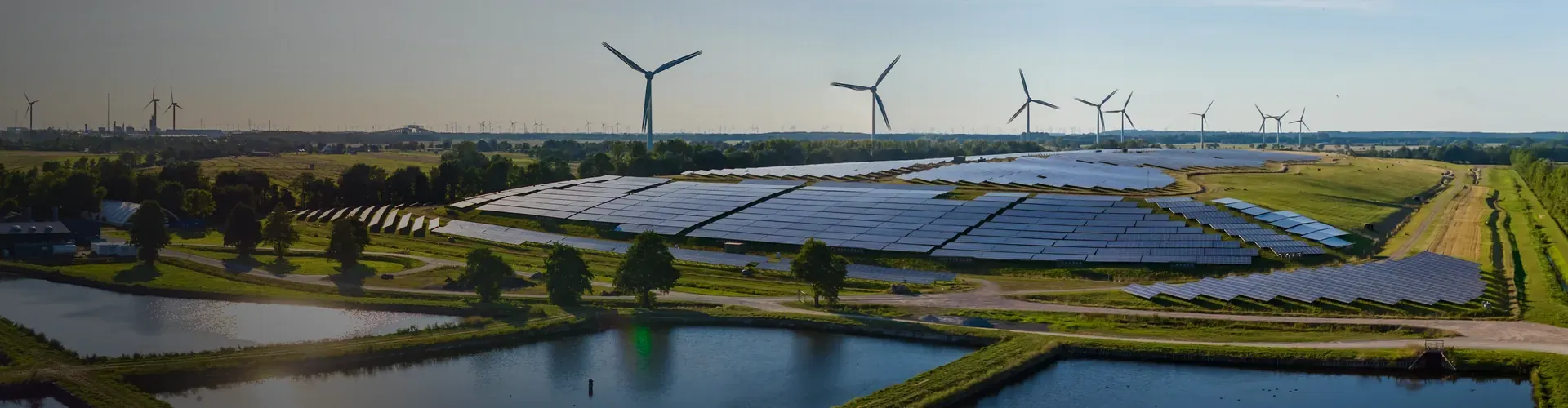 Parc solaire et &eacute;olien en zone rurale, entour&eacute; d'arbres et de prairies