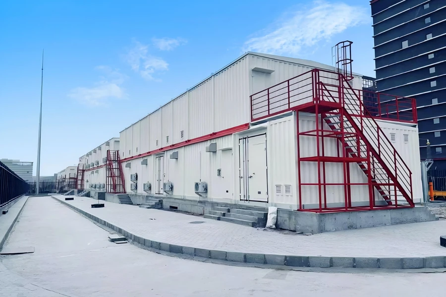 Rangée de modules E-House avec escaliers d'accès rouges le long d'un bâtiment de centre de données